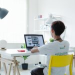 woman in white shirt sitting on chair using laptop computer